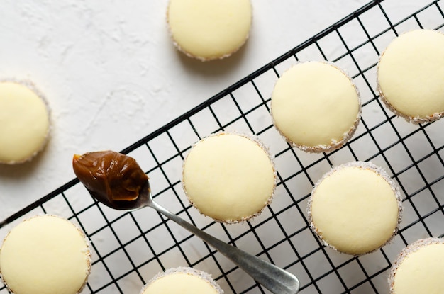 Cornstarch alfajores with coconut and a spoonful of dulce de leche on a black rack