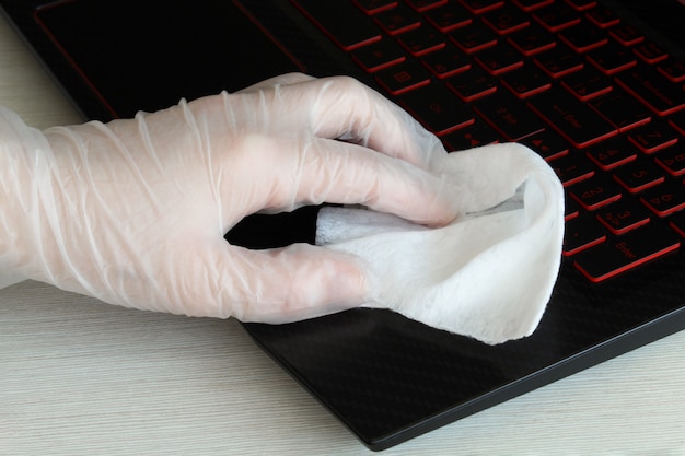 Corona virus cleaning and disinfection of your workspace. Woman wipes a computer keyboard with a sanitizer to protect against coronavirus. Stop the spread of coronavirus COVID-19.