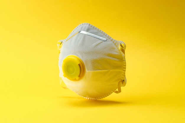 Coronavirus 2019-nCov novel protection infection concept. Hygienic mask or surgical earloop face mask on yellow background with clipping path