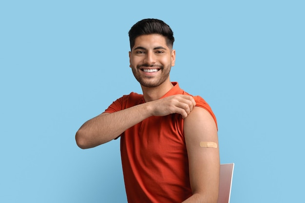 Coronavirus immunization portrait of vaccinated arab guy with adhesive band on shoulder