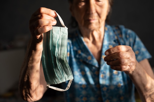 Coronavirus, masked woman, 86-year-old holding a protective mask against coronavirus. old woman wearing a face mask