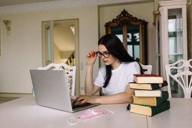 Coronavirus quarantine Woman working on laptop at balcony Work from home Woman wears protection mask Coronavirus world outbreak Remote education and work Stay home concept Spring lifestyle 2020