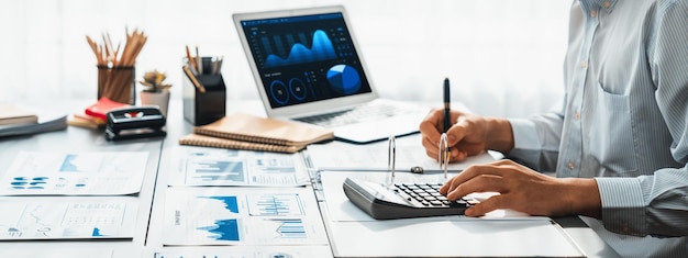 Corporate auditor calculating budget with calculator on his office desk Insight