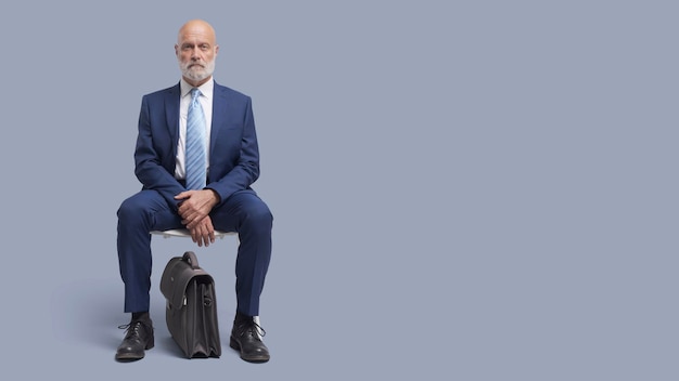 Corporate businessman sitting on a chair and waiting for a meeting or a job interview business and employment concept