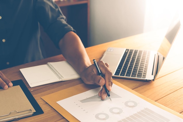 Corporate businessman working at office desk he is working with a laptop and chart paper