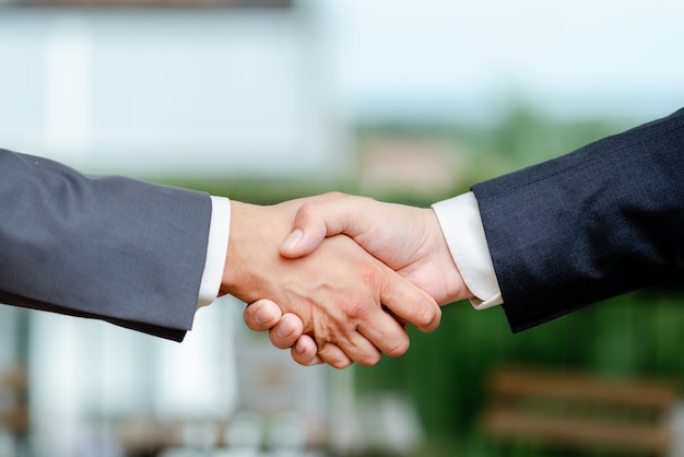 Corporate Businessmen Handshake Indoors.Two People Professionally Well Dressed Gesturing Togetherness.Working Colleague Partners Sign Deal In Agreement To Contract