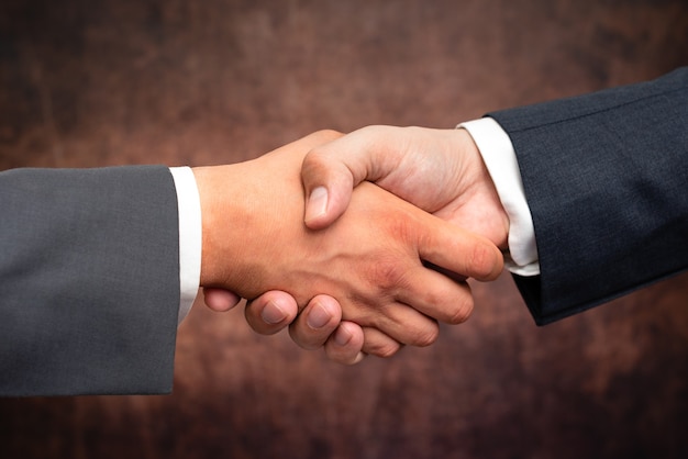 Corporate Businessmen Handshake Indoors.Two People Professionally Well Dressed Gesturing Togetherness.Working Colleague Partners Sign Deal In Agreement To Contract