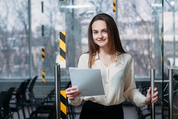 Corporate executive portrait. Business meeting over. Young smiling female leaving empty board room.