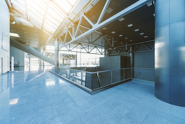 Corridor in the modern office building, with escalators, stairs, glass walls and reflective floor, natural light and flare