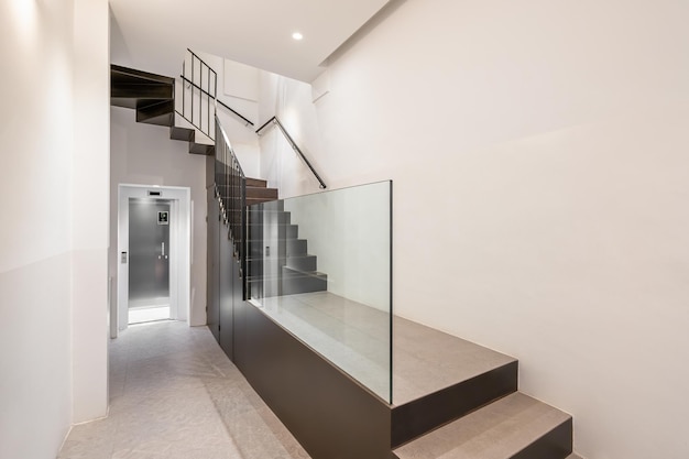 Corridor with passenger lift and stairs leading up interior of modern residential building