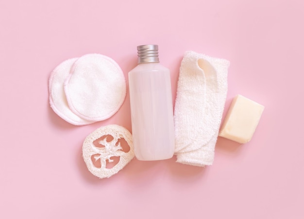 Cosmetic bottle and ecofriendly skin care accessories on pink mockup