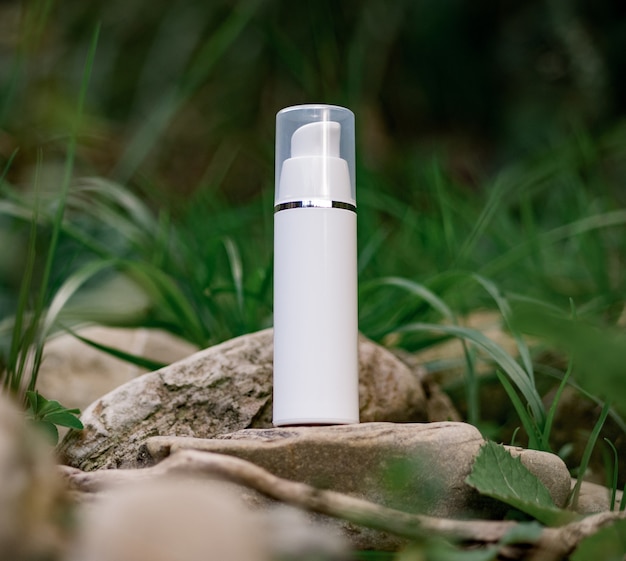 A cosmetic bottle  stands on a stone. Natural composition