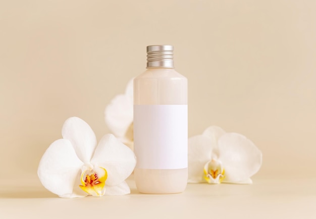 Cosmetic bottle with blank label near white orchid flowers on light yellow Mockup