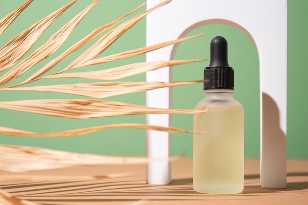 Cosmetic bottle with body and face oil on palm leaf summer natural cosmetics serum facial oil tropical concept