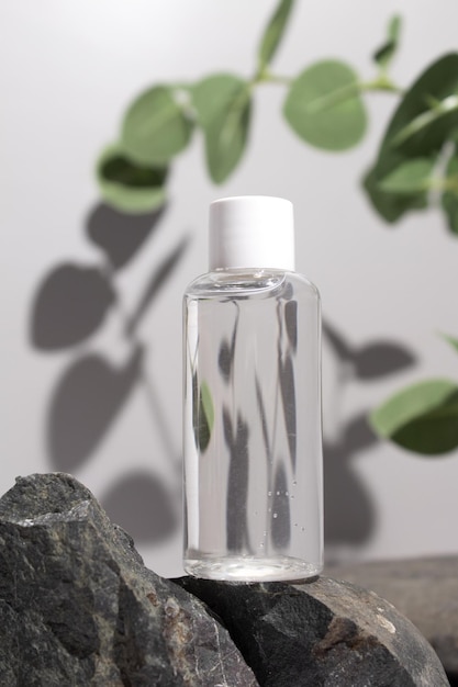 Cosmetic bottle with tonic water on stone stand with branch eucalyptus on grey background Natural cosmetics concept skin care product Beauty concept for face body care