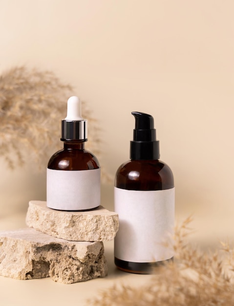 Cosmetic bottles on beige stones near dry pampas grass on light beige close up Labels Mockup