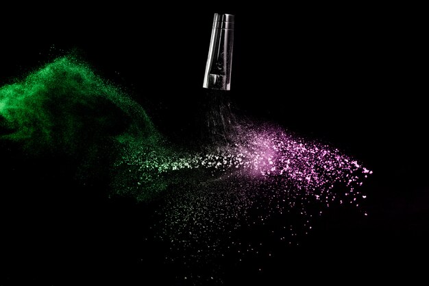 Cosmetic brush with green and pink cosmetic powder spreading for makeup artist and graphic design in black background