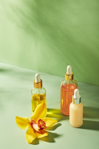 Cosmetic care products in glass bottles with orchid flowers  serums cream gel oils concept for face ...