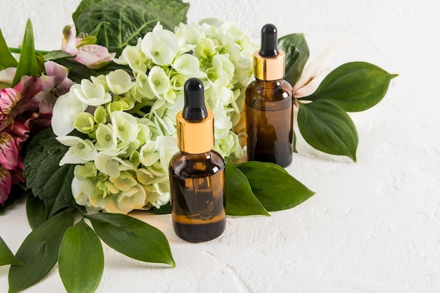 Cosmetic flavons with a pipette with an organic product for selfcare hydrangea flowers against the background packaging with an empty label