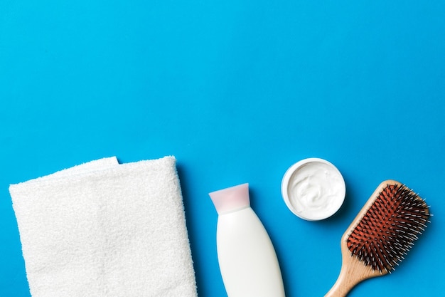 Cosmetic for hair care cream and towel on a colored background top view flat lay