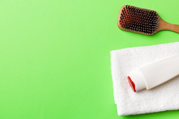 Cosmetic for hair care cream and towel on a colored background top view flat lay