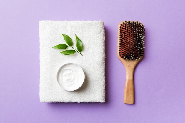 Cosmetic for hair care cream and towel on a colored background top view flat lay