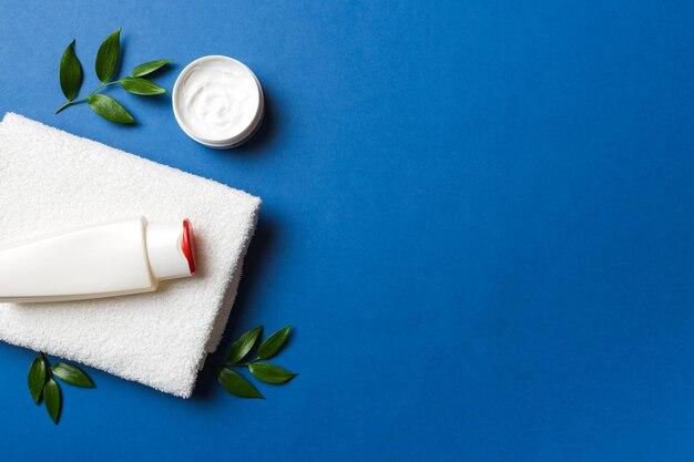 Cosmetic for hair care cream and towel on a colored background top view flat lay