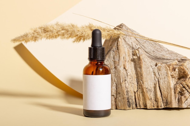 Cosmetic jar with cream, serum or organic essential oil for the face and body, against the background of a log and hard shadows. The concept of a beauty salon and natural cosmetics.