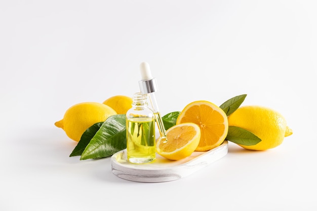 Cosmetic lemon oil whey with vitamin C in an open bottle with a pipette filled with cosmetics ripe lemons white background