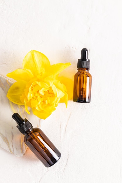 cosmetic packaging unnamed bottles to advertise the product Top view of two amber bottles with a yellow spring daffodil flower Vertical view