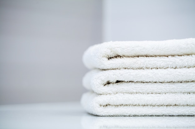 Cosmetic products and cotton towels on white wooden table in beauty salon