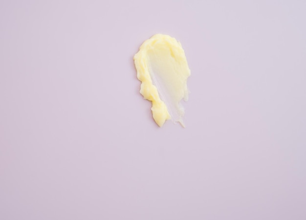 Cosmetic products creamy yellow stain texture on pink background Texture of natural cosmetics