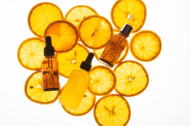 Cosmetic products oil serum gel juicy ripe orange bottles white background