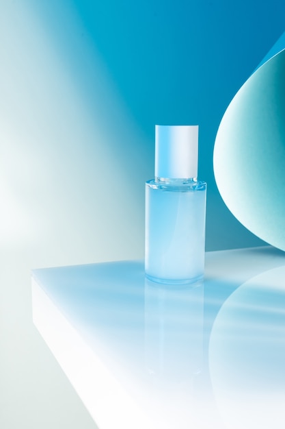 Cosmetic serum bottle on a white table, blue neon light, mock up