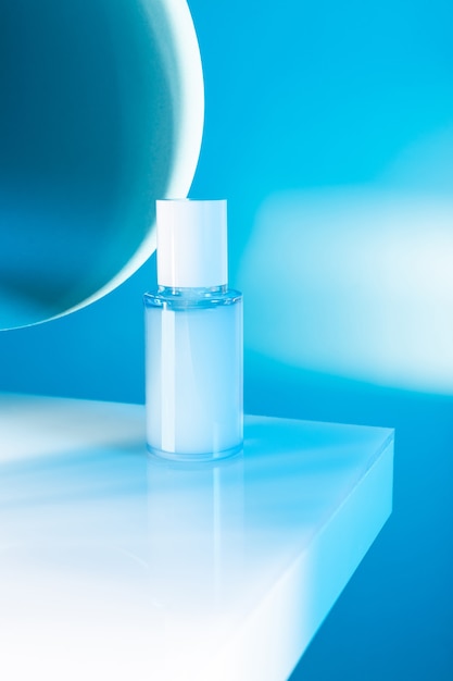 Cosmetic serum bottle on a white table, blue neon light, mock up