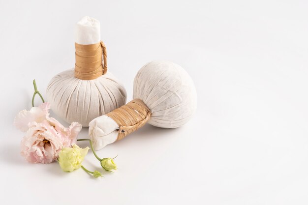 Cosmetic set for massage with bags of herbs and delicate flower on white