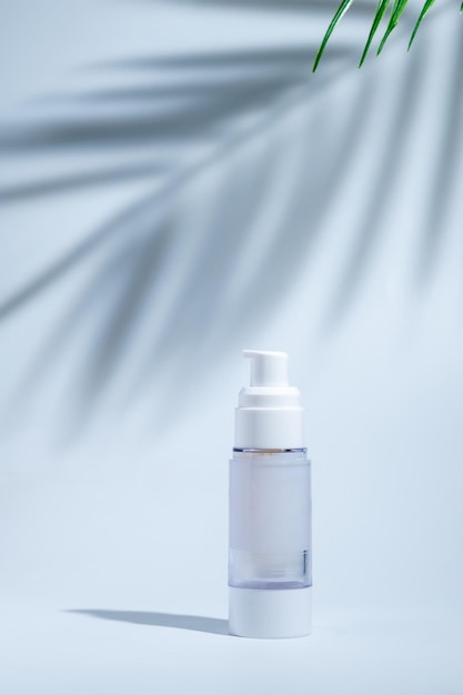 Cosmetic and skin care package in a glass bottle on white background with hard or Harsh shadows and sunlight of leaves tree branch falling on wall modern and minimal beauty product design