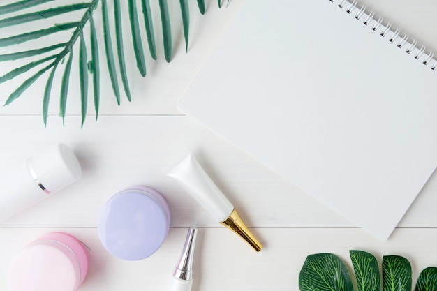 Cosmetic and skin care product and notebook and leaves on table