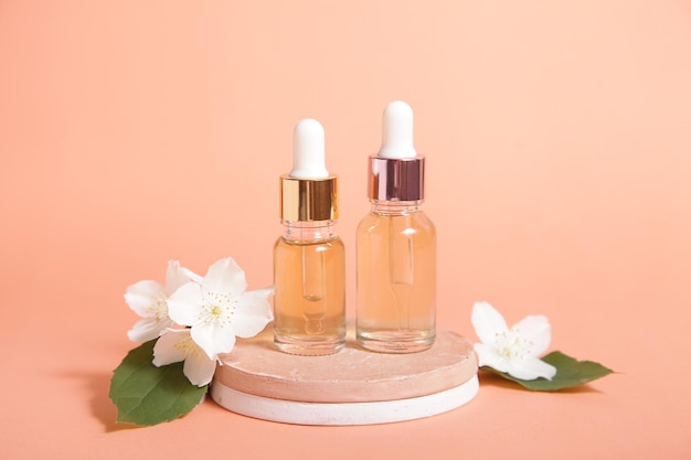 Cosmetic two bottle oil podium and flower on Pastel coral color background Mock up