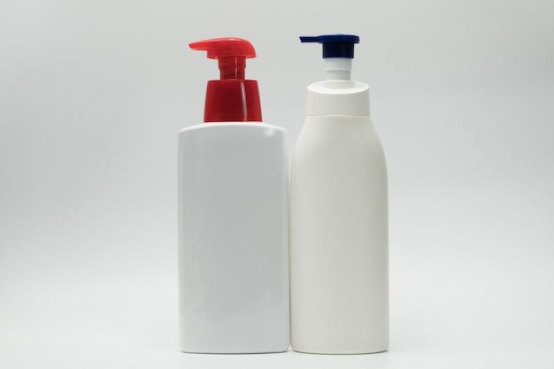 Cosmetic white plastic bottle with blue and red pump dispenser isolated on white background with blank label and copy space. Skin care bottle. Body care lotion. Cosmetic jar package. Shampoo bottle.