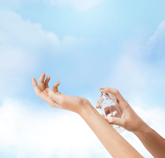 cosmetics, body parts and beauty concept - close up of woman hands spraying perfume