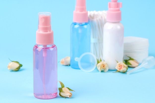 Cosmetics for face and body in pink bottles with fresh roses on a gentle blue background. creams and lotion. spa.