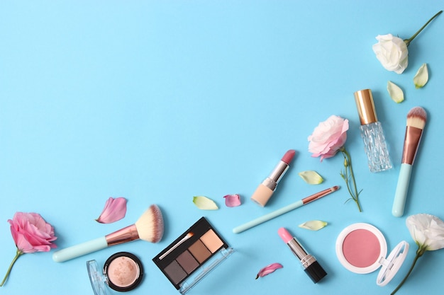 Cosmetics and flowers on a colored background top view