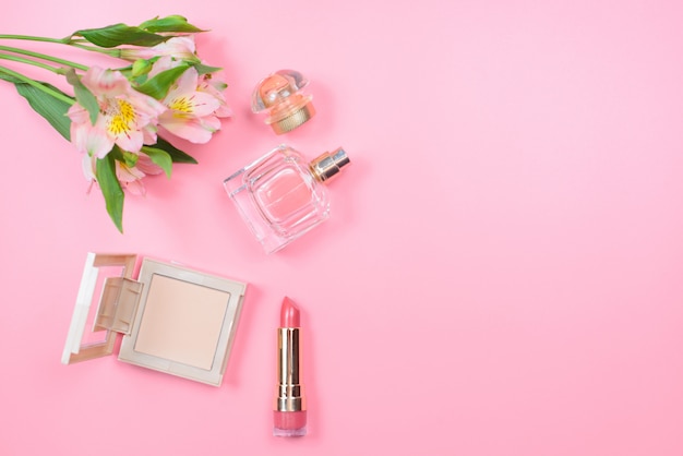 Cosmetics and flowers on a pink table with copyspace