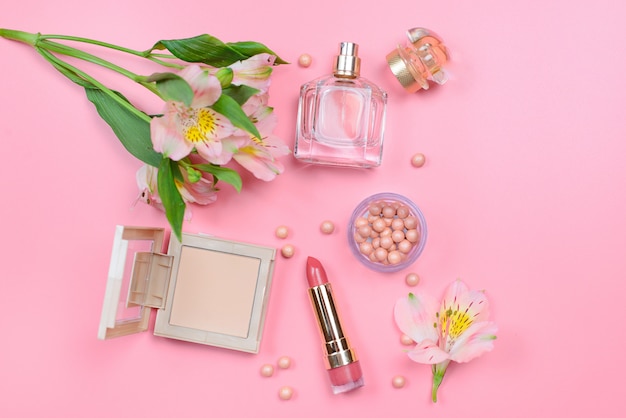 Cosmetics and flowers on a pink table with copyspace