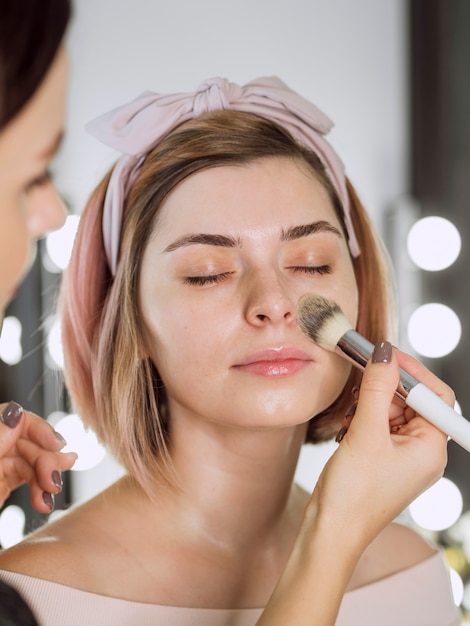 Cosmetologist applying foundation on woman