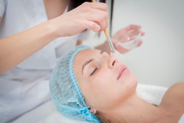 Cosmetologist applying a mask to client