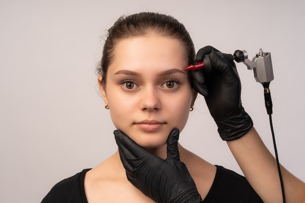 Cosmetologist applying permanent make up on eyebrows.