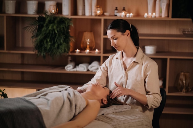 A cosmetologist girl does a facial and neck massage to a girl in the office for skin elasticity