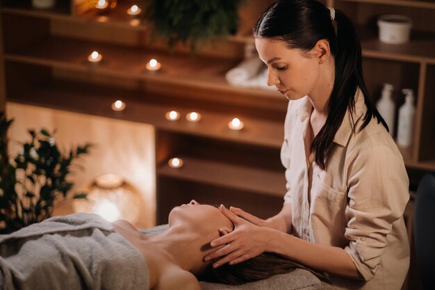 A cosmetologist girl does a facial and neck massage to a girl in the office for skin elasticity